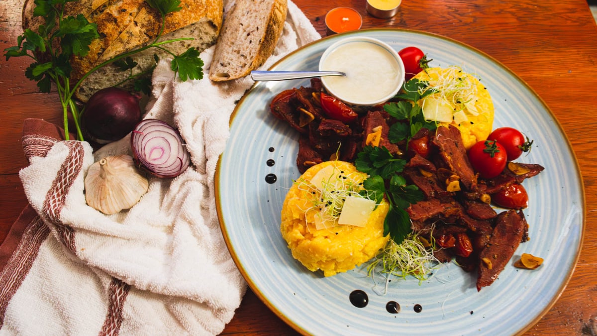 Delicious Romanian cuisine featuring polenta, vegetables, and artisan bread in a vibrant setting.